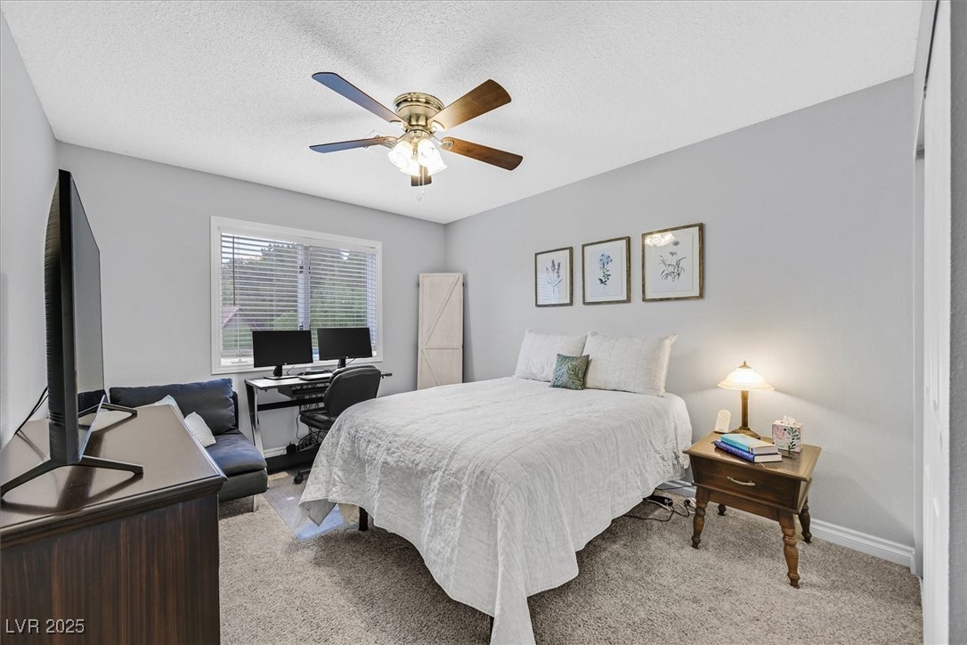 18 Hummingbird Circle Henderson, NV 89014 - Photo 24 of 39 Bedroom with light carpet, a ceiling fan, a textured ceiling, and a desk