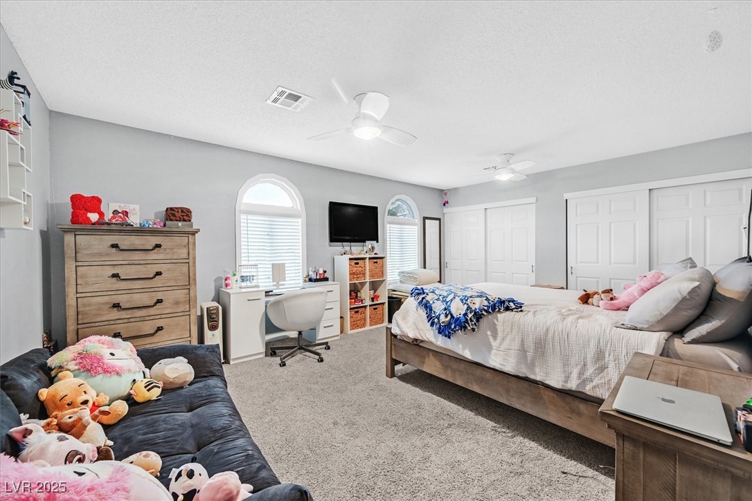 18 Hummingbird Circle Henderson, NV 89014 - Photo 27 of 39 Carpeted bedroom featuring multiple closets, a ceiling fan, a textured ceiling, and a desk