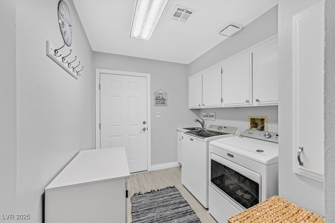 18 Hummingbird Circle Henderson, NV 89014 - Photo 28 of 39 Laundry area featuring light wood finished floors, washer and dryer, and cabinet space