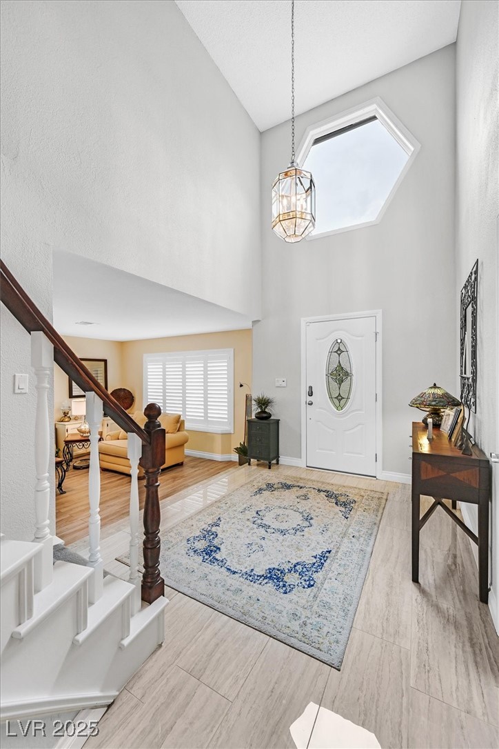 18 Hummingbird Circle Henderson, NV 89014 - Photo 3 of 39 Foyer entrance featuring a high ceiling, plenty of natural light, stairway, a chandelier, and wood finish floors