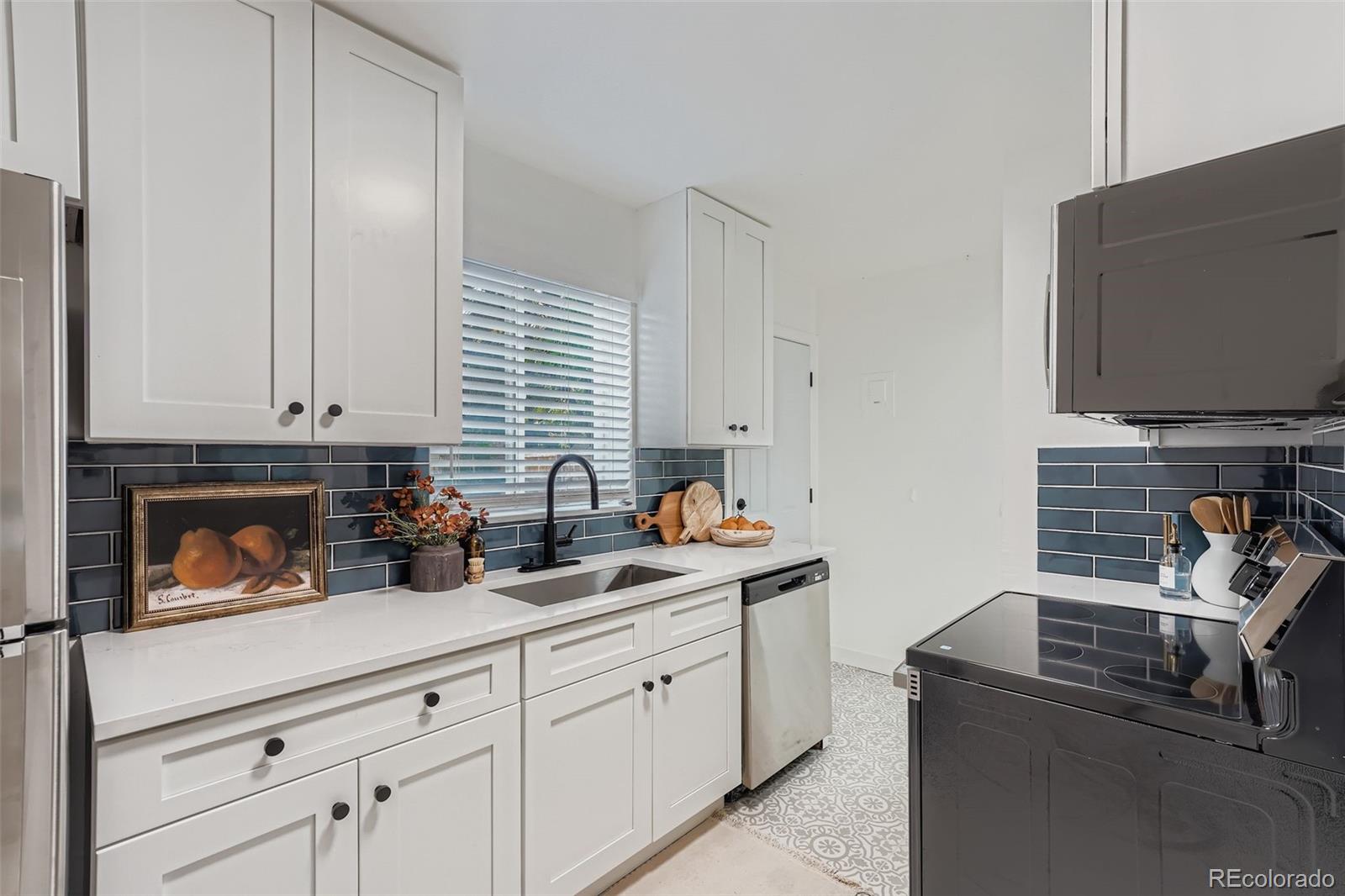 2985 Ivanhoe Street Denver, CO 80207 - Photo 8 of 25 a kitchen with stainless steel appliances white cabinets and a wooden floor
