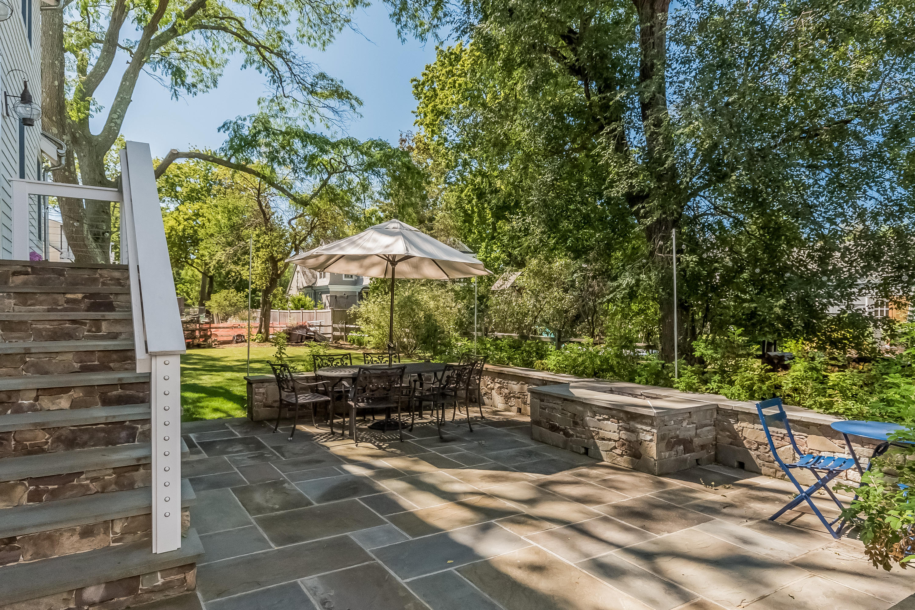 20 Plymouth Road Darien, CT 06820 - Photo 31 of 46 a view of a patio with table and chairs under an umbrella with large trees