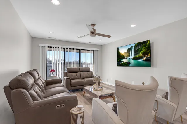 a living room with furniture a ceiling fan a rug and a window