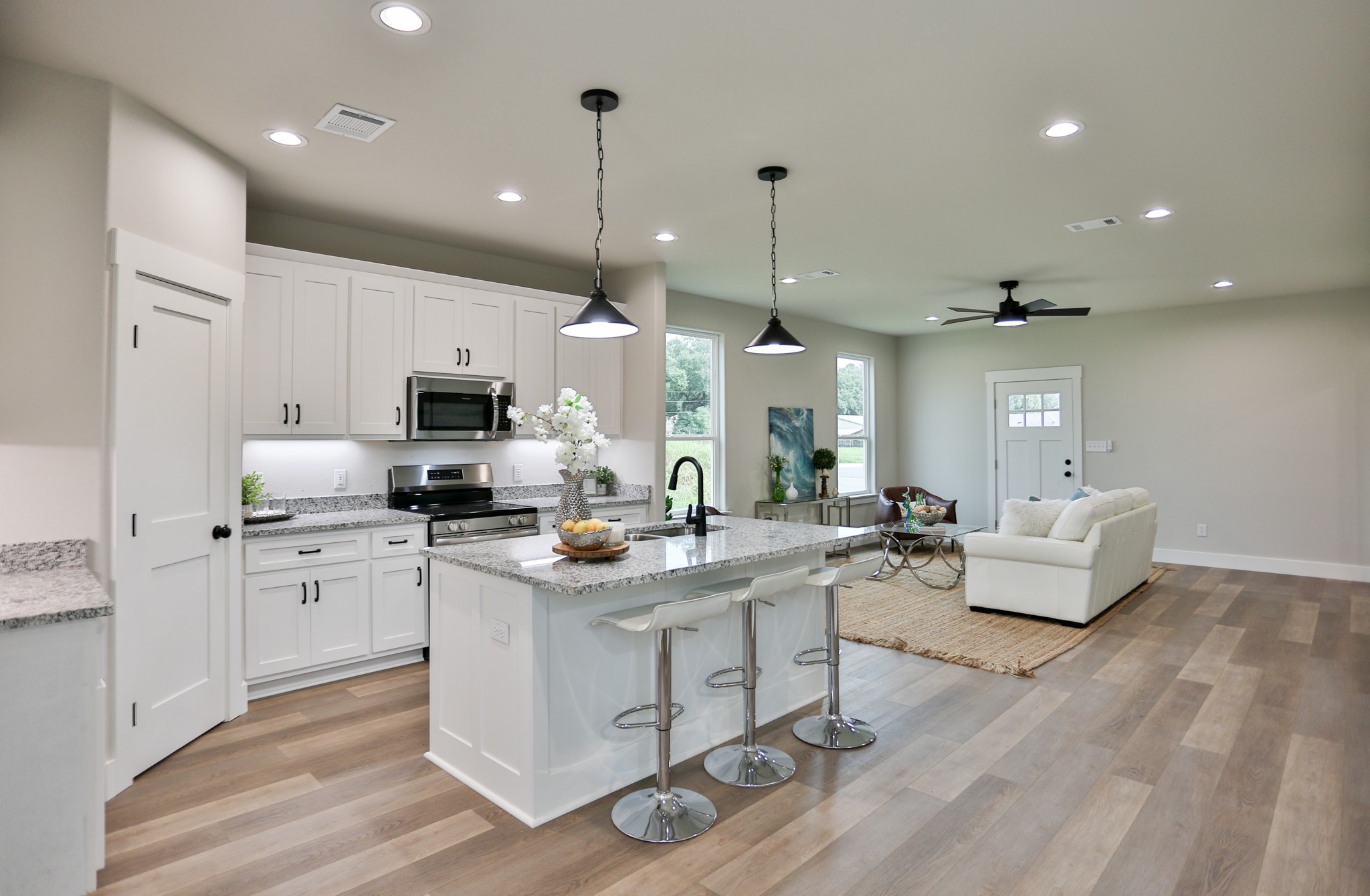 325 String Prairie Way Smithville, TX 78957 - Photo 5 of 23 a kitchen with stainless steel appliances kitchen island granite countertop a stove a sink a refrigerator and white cabinets with wooden floor