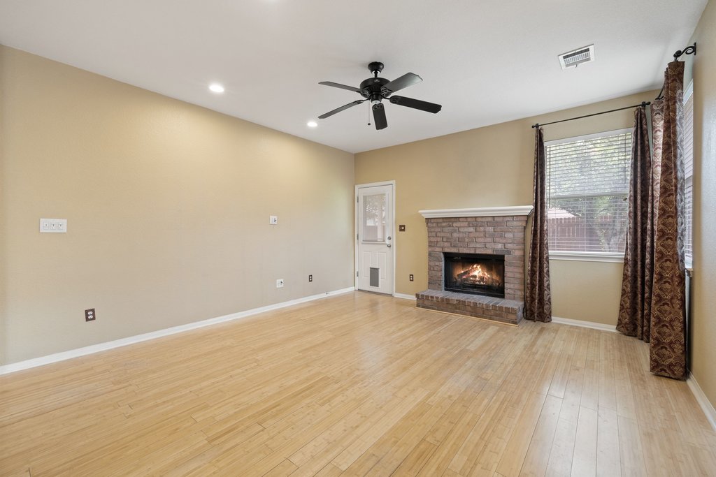 347 Spring Drive Kyle, TX 78640 - Photo 20 of 40 A cozy living space features hardwood flooring and a brick fireplace, offering a welcoming ambiance.