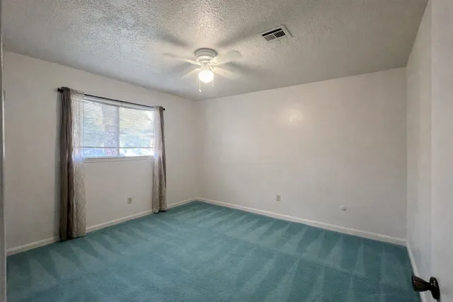 an empty room with a window and a fan