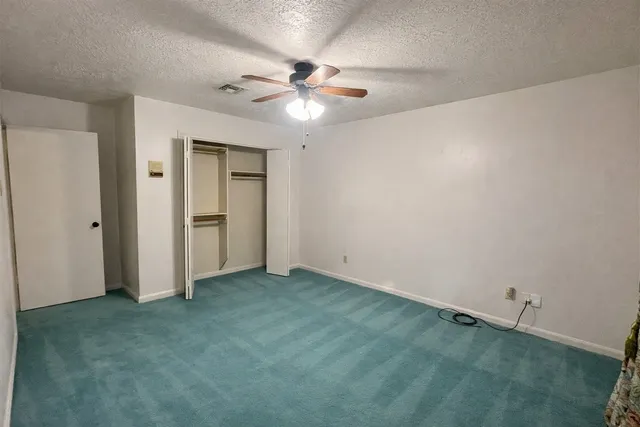 an empty room with closet and a chandelier fan