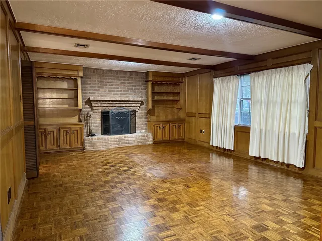 a view of an empty room with a fireplace and a window