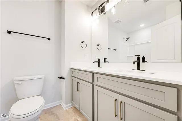 a bathroom with a toilet a sink a mirror and vanity