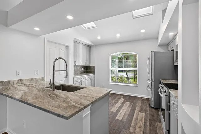 a kitchen with kitchen island a counter top space appliances and a sink