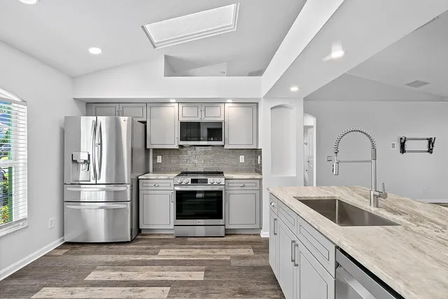 a kitchen with stainless steel appliances granite countertop a sink stove and refrigerator