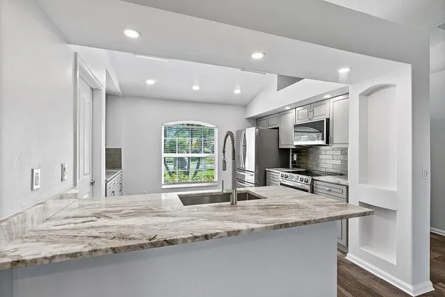 a kitchen with granite countertop a sink and a stove top oven