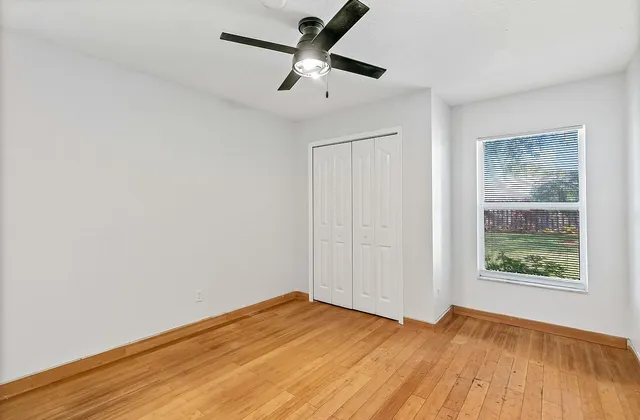 a view of empty room with wooden floor and fan