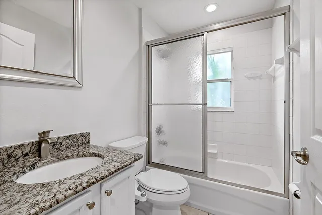 a bathroom with a granite countertop sink toilet and shower