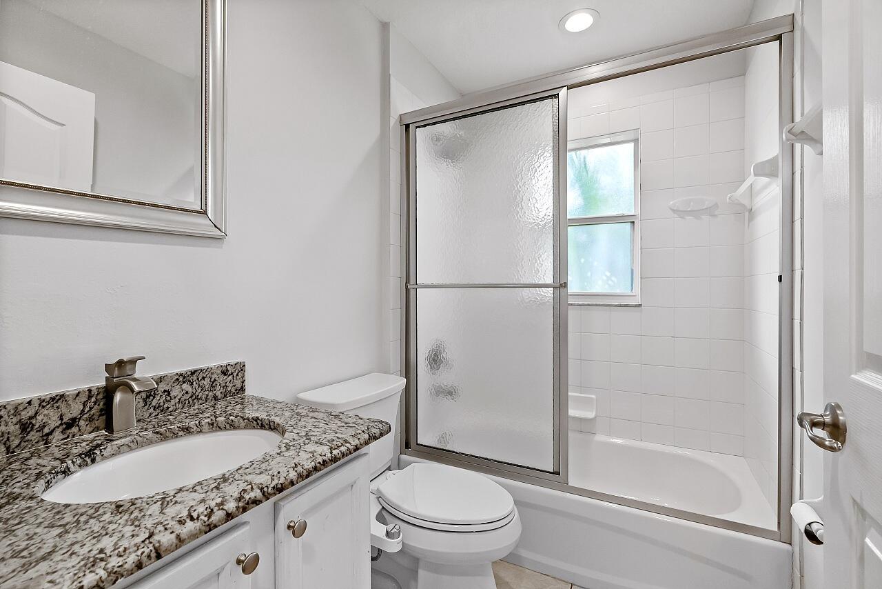 1374 Southeast Concha Street Port St. Lucie, FL 34983 - Photo 22 of 29 a bathroom with a granite countertop sink toilet and shower