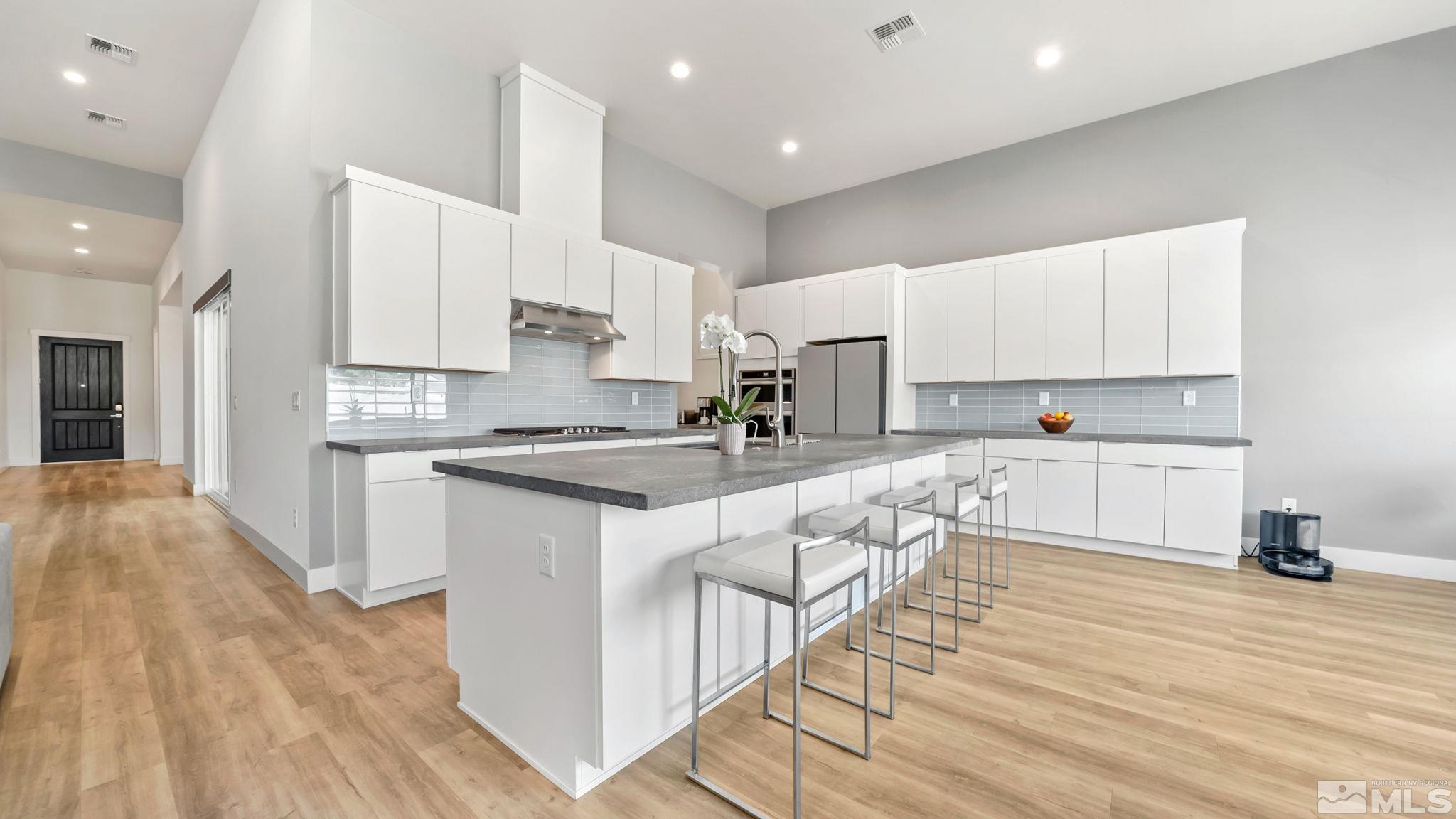 13550 Water Willow Street Reno, NV 89521 - Photo 7 of 37 a large kitchen with stainless steel appliances granite countertop a stove a sink a refrigerator and white cabinets with wooden floor