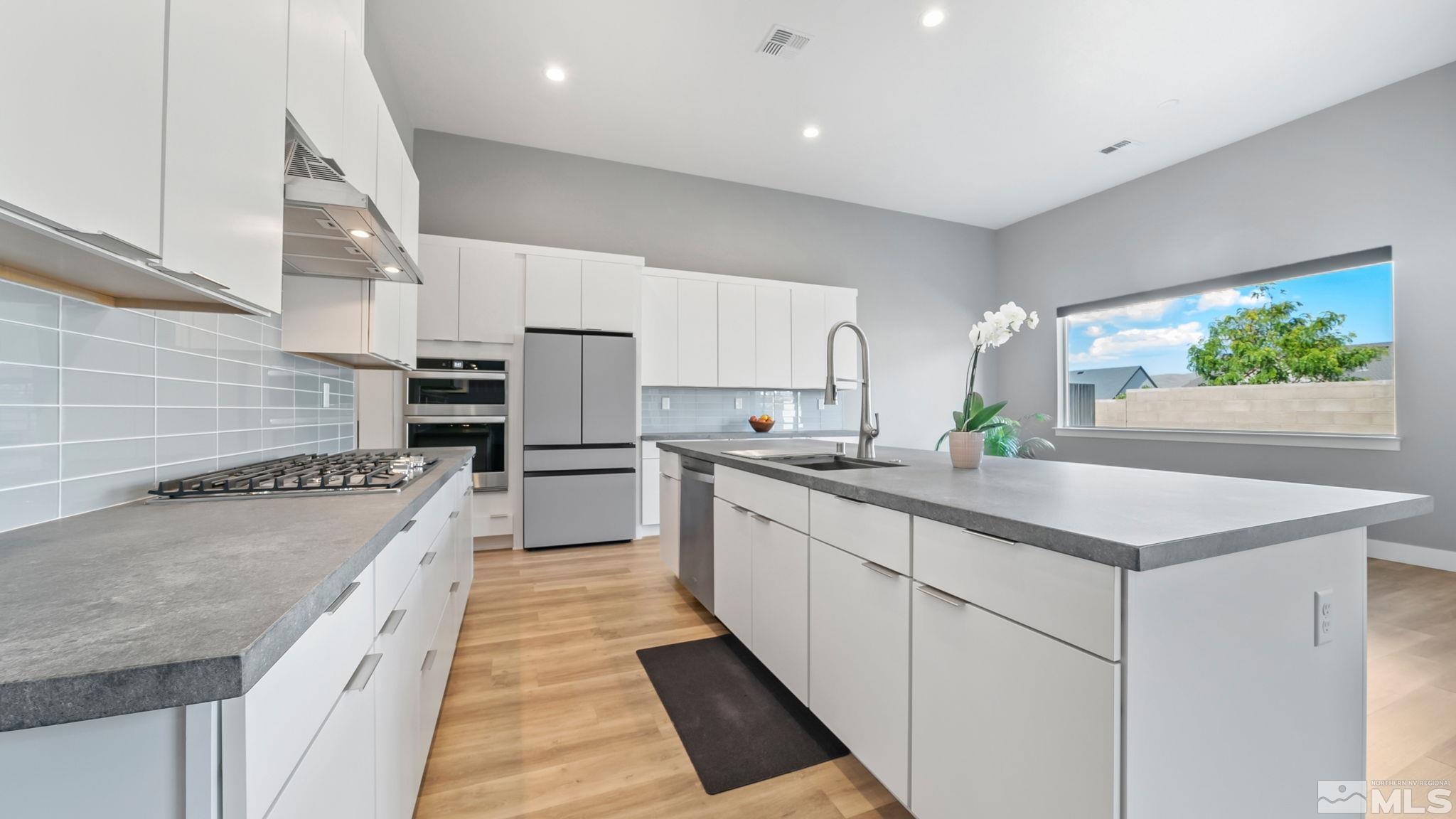 13550 Water Willow Street Reno, NV 89521 - Photo 8 of 37 a large white kitchen with stainless steel appliances kitchen island granite countertop a sink and cabinets