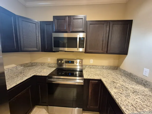 a kitchen with granite countertop wooden cabinets and stainless steel appliances