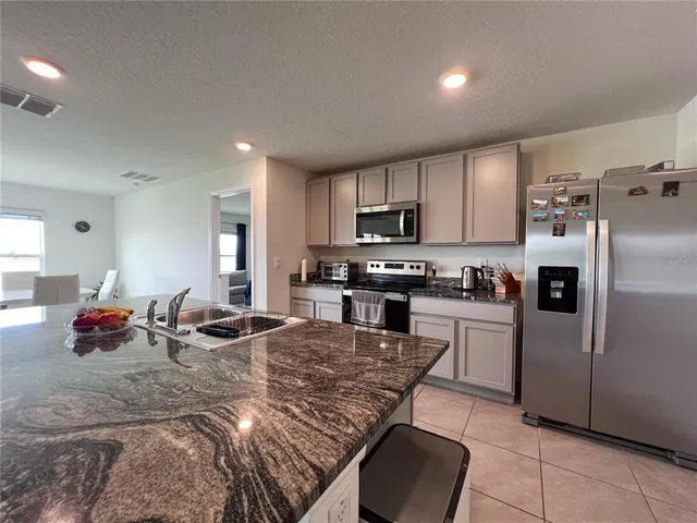 a kitchen with kitchen island granite countertop a stove refrigerator and microwave