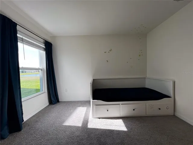 a view of an empty room with a window and dresser