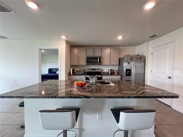 a kitchen with stainless steel appliances granite countertop a table chairs sink refrigerator and granite counter tops