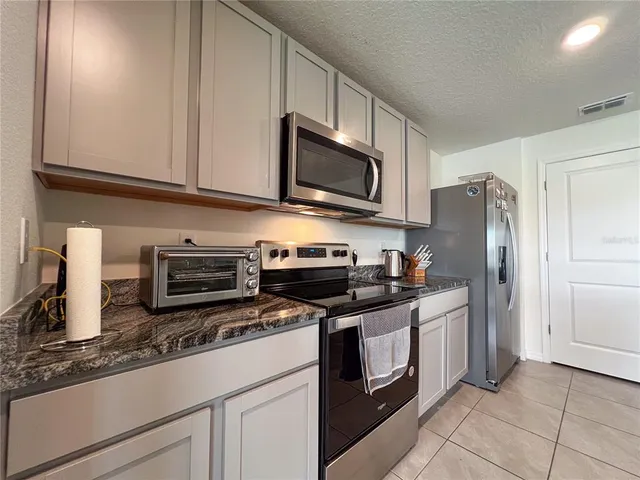 a kitchen with granite countertop a refrigerator stove and microwave