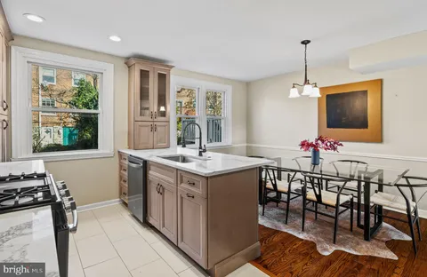 a kitchen with stainless steel appliances granite countertop a stove top oven a sink dishwasher a dining table and chairs with wooden floor