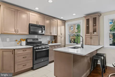 a kitchen with stainless steel appliances granite countertop a stove a sink dishwasher a microwave oven and a refrigerator with wooden cabinets