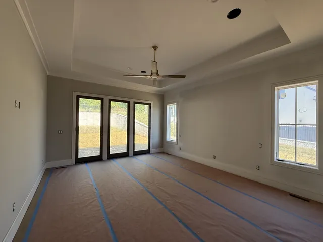 an empty room with wooden floor a ceiling fan and windows