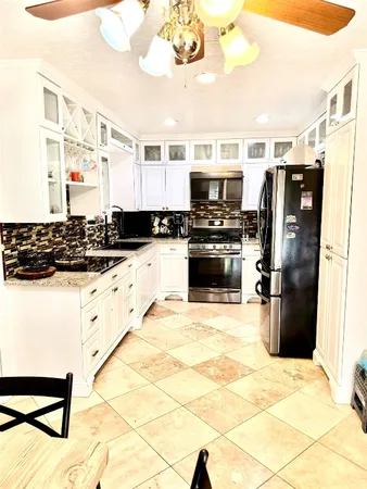 a kitchen with stainless steel appliances a stove a sink a refrigerator white cabinets and dining table with wooden floor