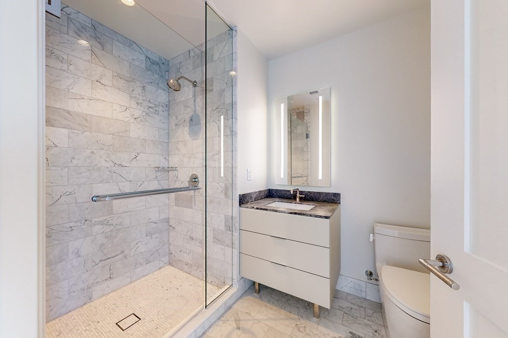 240 Devonshire Street, Unit 3901 Boston, MA 02110 - Photo 11 of 40 a bathroom with a granite countertop sink a toilet a mirror and shower