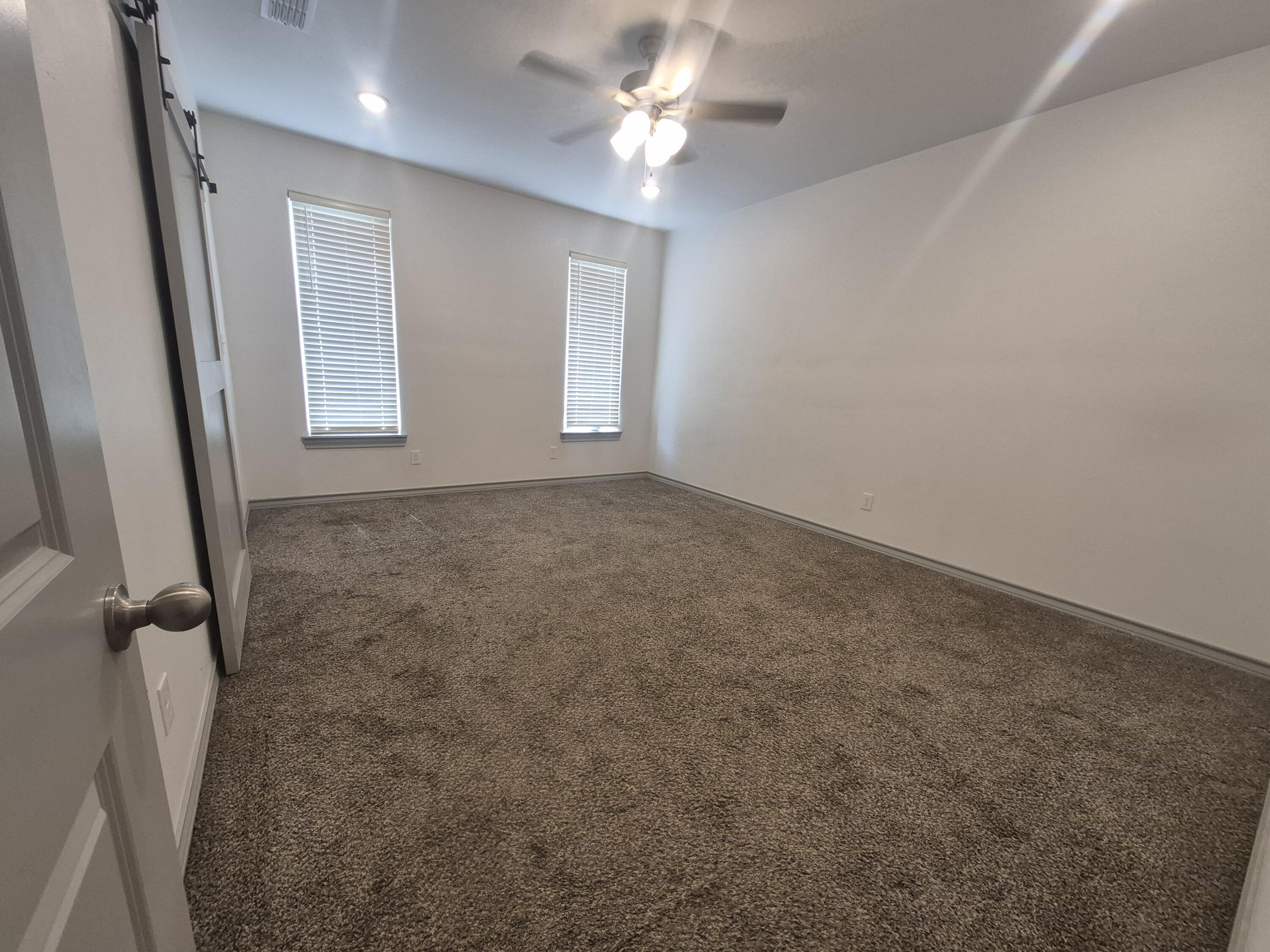 4718 125th Street Lubbock, TX 79424 - Photo 12 of 18 an empty room with windows and fan