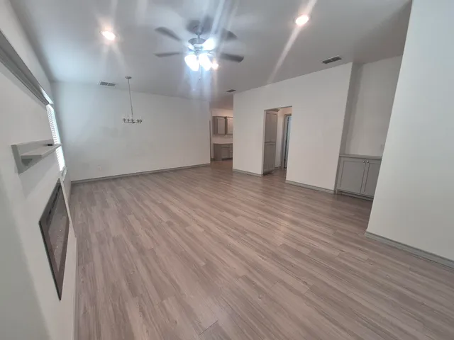 an empty room with wooden floor and a ceiling fan