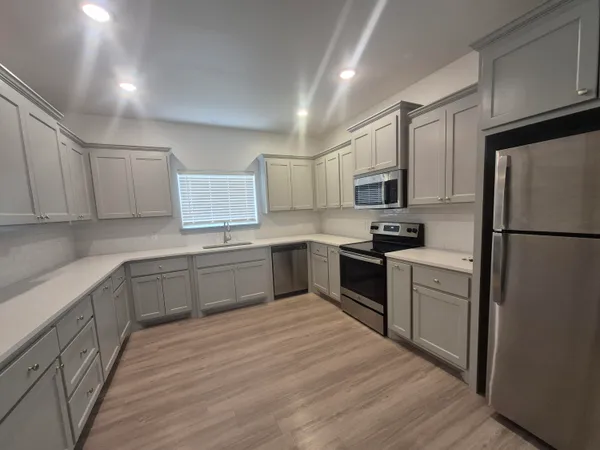 a kitchen with granite countertop a refrigerator stove top oven and sink