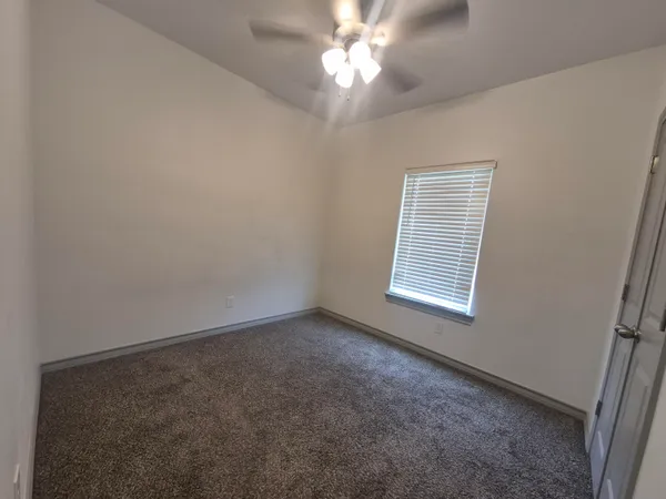 an empty room with a window and a fan