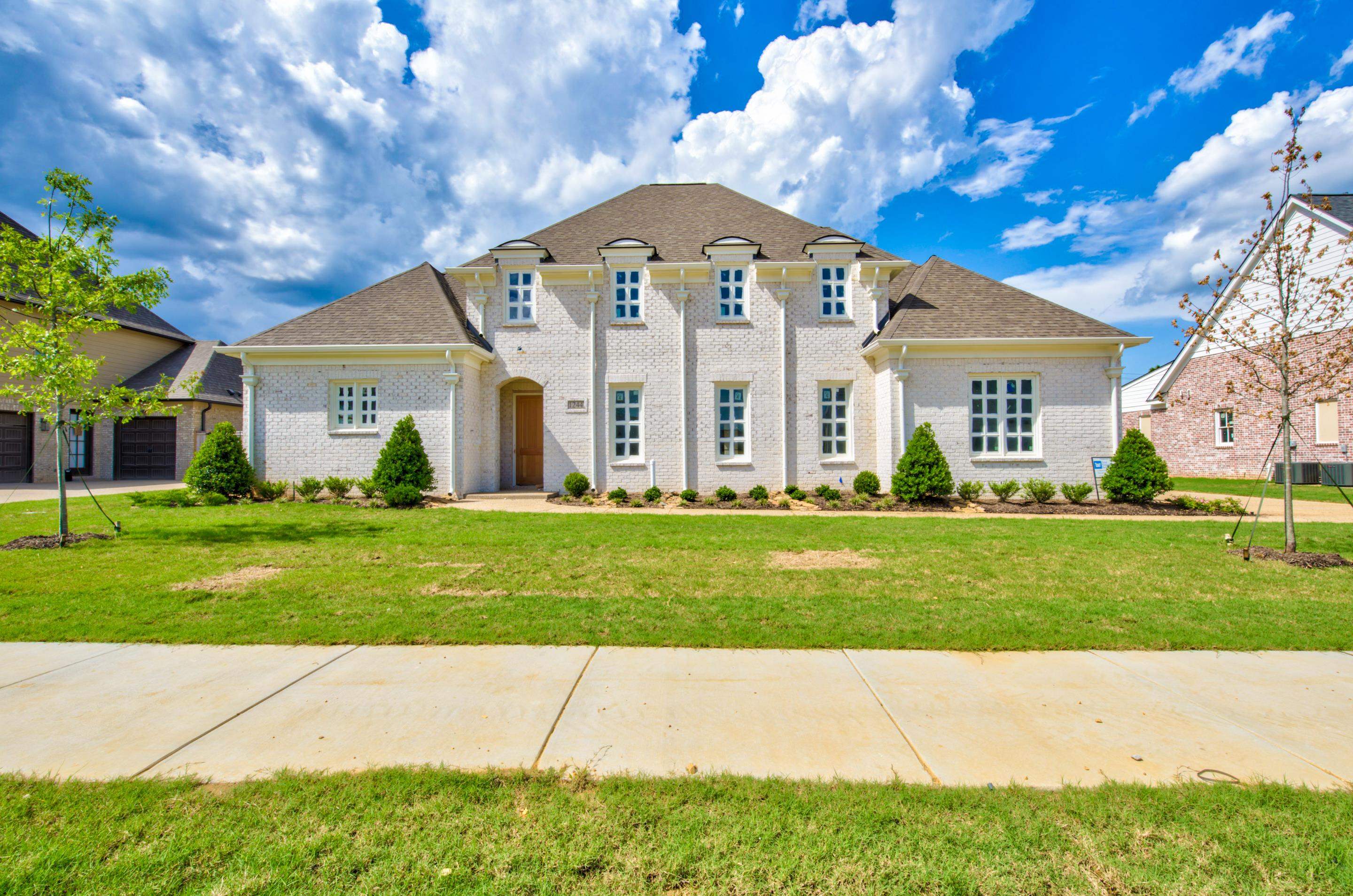 a front view of a house with a garden and trees