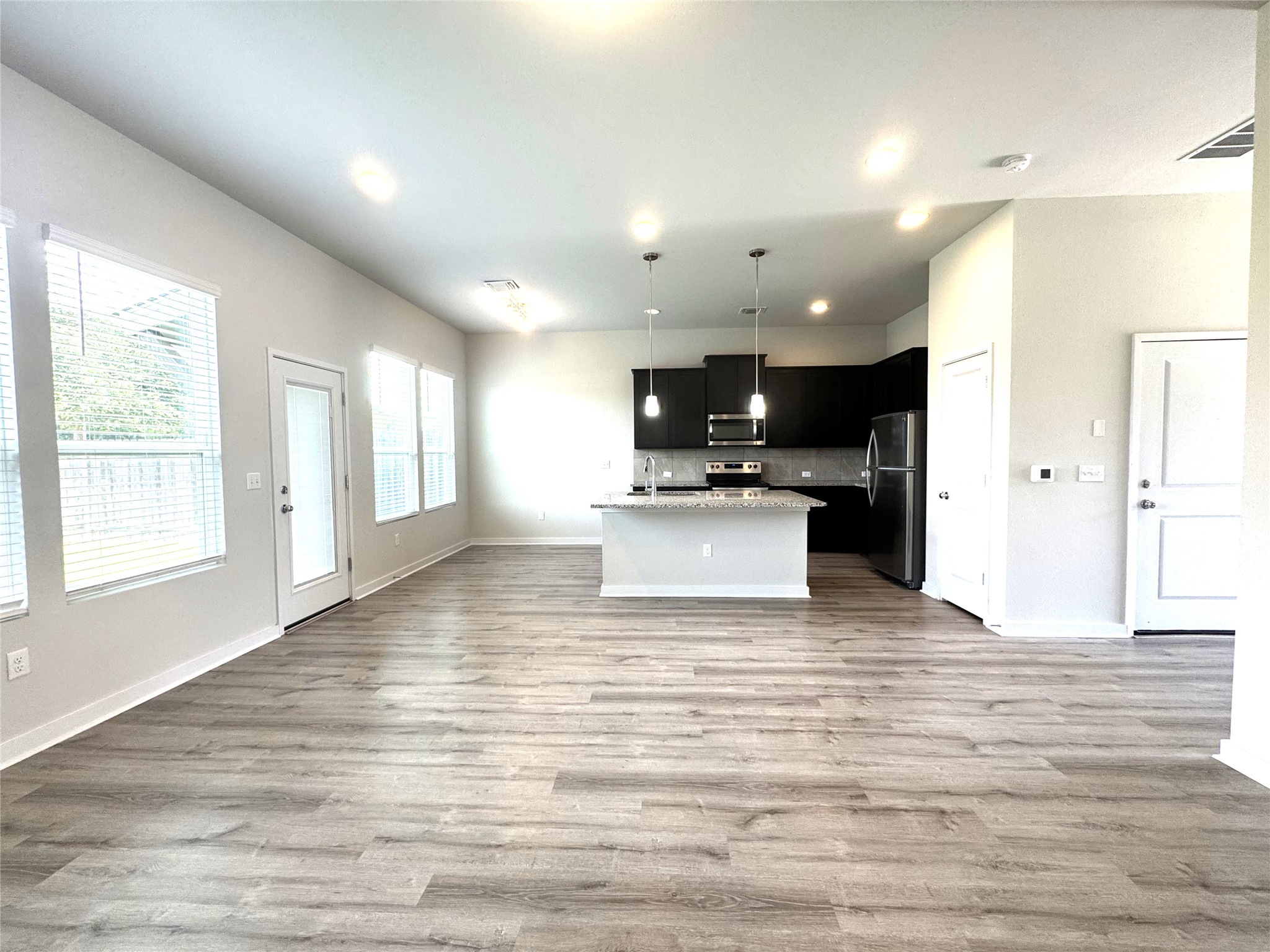 15102 Ryman Road Pflugerville, TX 78660 - Photo 3 of 12 a view of a kitchen with kitchen island a sink wooden floor and a refrigerator