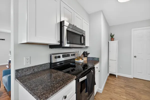 a kitchen with stainless steel appliances granite countertop a stove top oven a sink dishwasher a dining table and chairs with wooden floor
