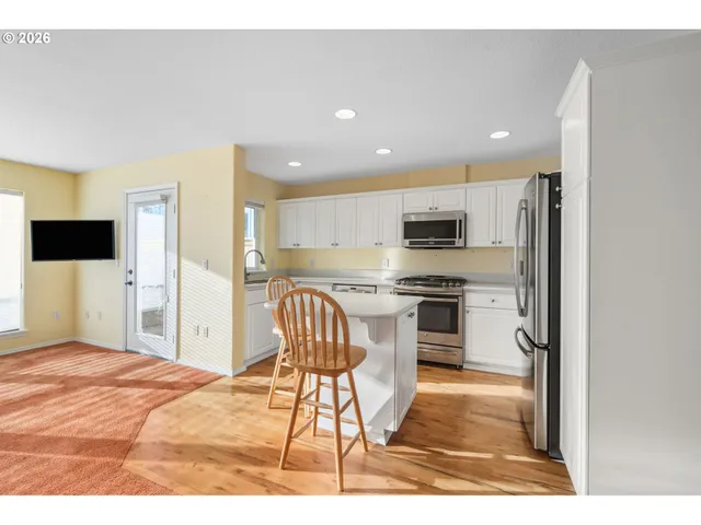 a kitchen with stainless steel appliances kitchen island granite countertop a stove top oven a sink and a refrigerator