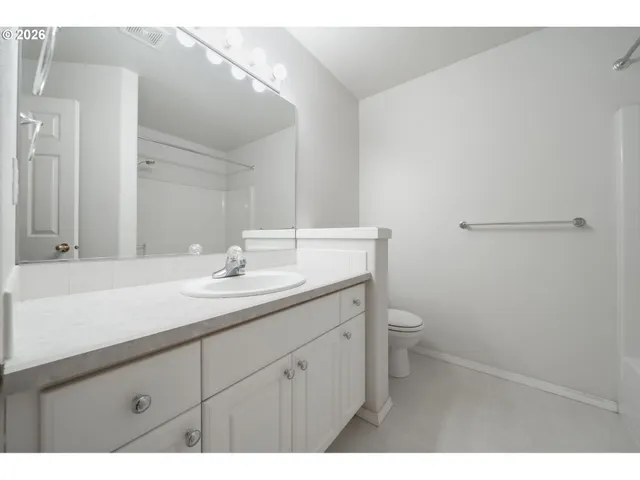 a bathroom with a granite countertop sink a toilet and a mirror