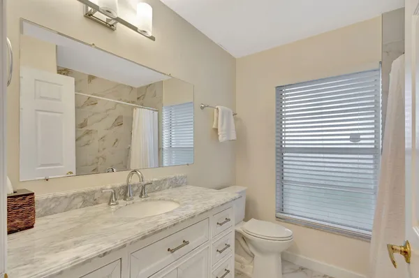 a bathroom with a granite countertop toilet a sink and a mirror