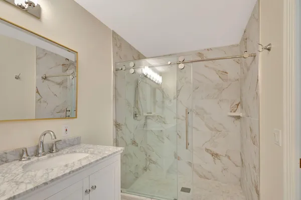 a bathroom with a granite countertop sink a mirror a shower and a shower
