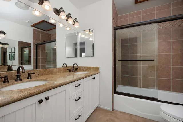 a bathroom with a granite countertop sink a large mirror and shower