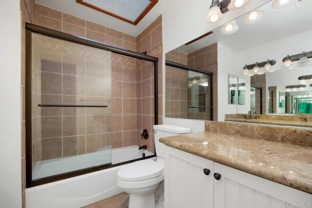a bathroom with a granite countertop sink toilet and shower