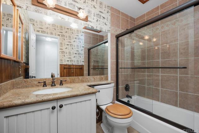 a bathroom with a granite countertop sink a toilet a mirror and shower