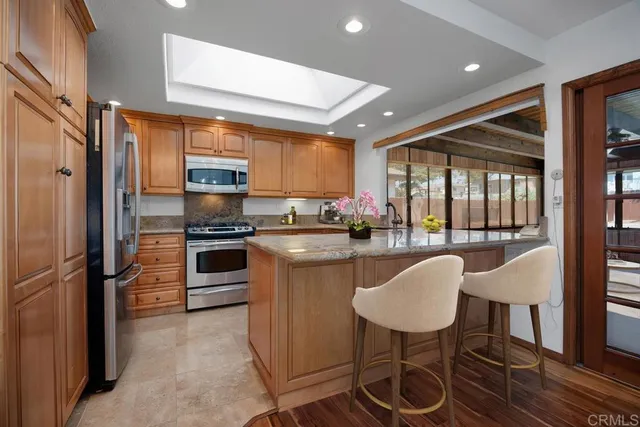 a kitchen with stainless steel appliances a refrigerator a stove a sink and white cabinets with wooden floor