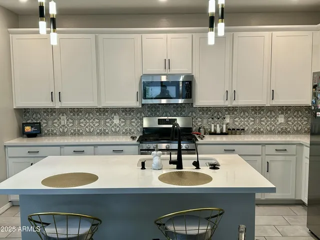 a kitchen with stainless steel appliances granite countertop a sink a stove and white cabinets