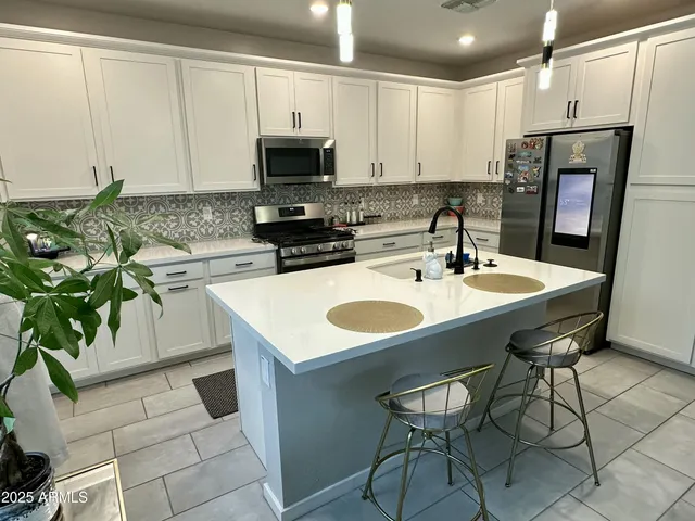 a kitchen with stainless steel appliances a white table chairs and a refrigerator