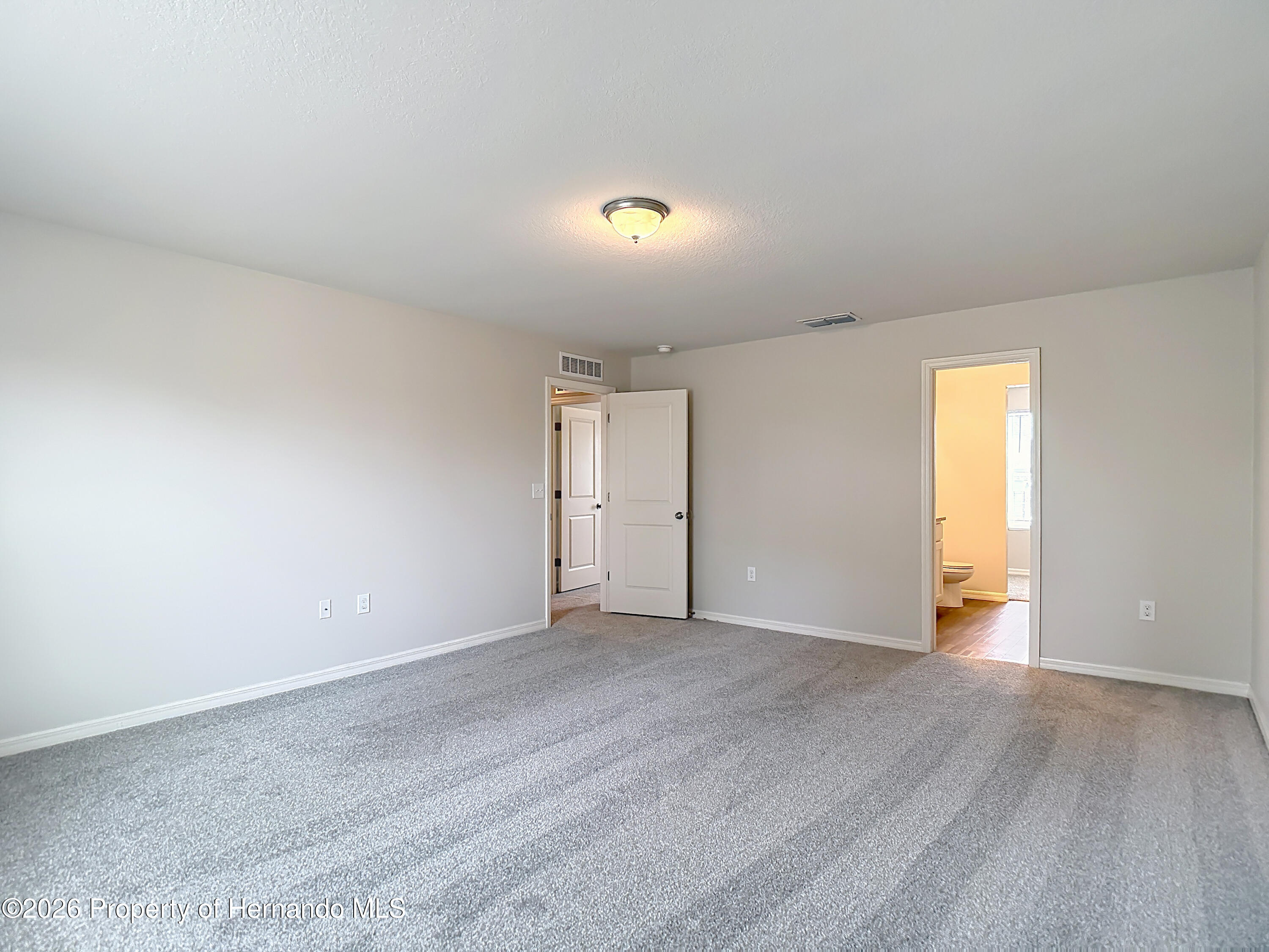 11374 Marcella Avenue Weeki Wachee, FL 34614 - Photo 39 of 70 an empty room with wooden floor and windows
