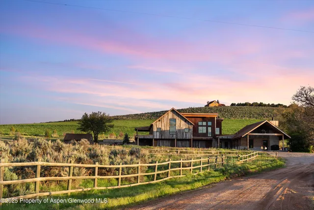 a view of a big house with a big yard and large trees